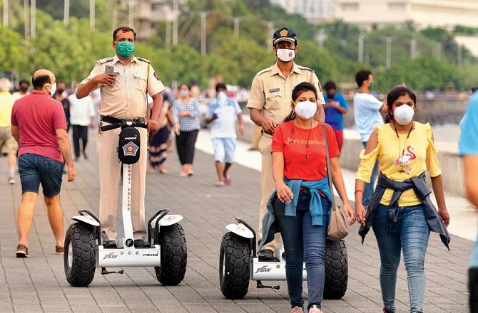 Mumbai police officers on electric bikes watch joggers at Marine Drive. Pic/Bipin Kokate