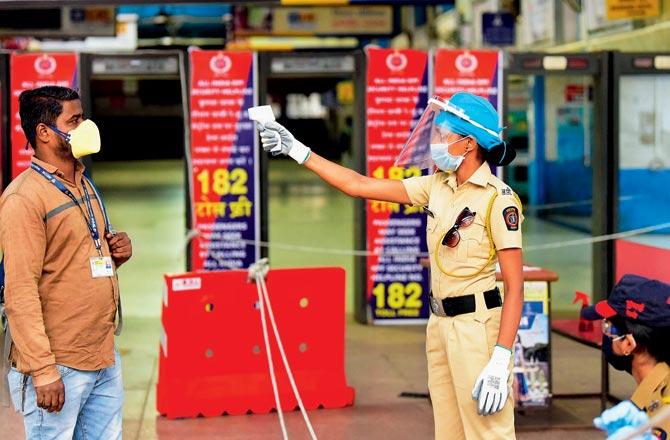 A security personnel takes the temperature of a commuter at Churchgate station. Pic/Bipin Kokate