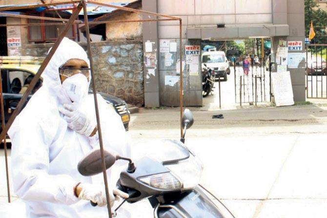Santosh Daundkar kitted out in a PPE suit, mask and gloves, Daundkar takes the utmost precautions while transporting patients to hospitals  on his scooter