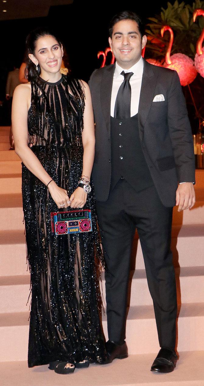 Akash Ambani and Shloka Mehta were once again snapped at an auction event hosted by Isha Ambani. Twinning in black, Akash looked smart in a black suit, while Shloka looked stunning in a sheer gown embellished with tassels all over. But the highlight of the event was Shloka's quirky clutch which was in the shape of a boombox.