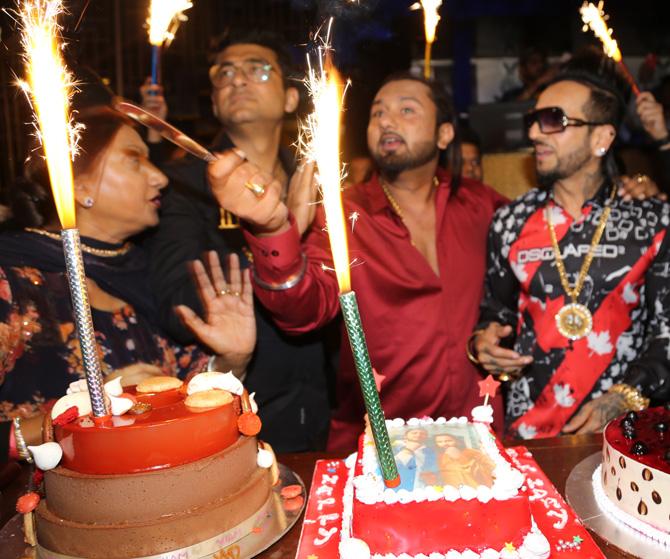 Yo Yo Honey Singh, whose birth name is Hirdesh Singh, gained instant stardom by belting out hits such as Main Sharabi, Angrezi beat and Lungi dance.
In picture: Honey Singh all set to cut his birthday cake with his mother Bhupinder Kaur (L) and Jazzy B (extreme R) by his side.
