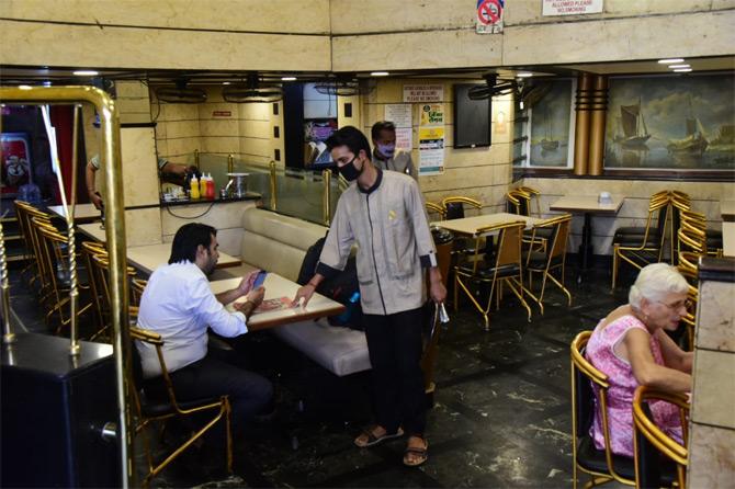 In photo: A restaurant server dons a face mask as he guides a customer through the menu.