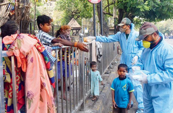 Members of the Jain Manav Sena Mandal seen distributing packets of food with masala rice, puri and sabzi, to the homeless and labourers across Marine Lines,   Chira Bazaar and Kalbadevi, on Saturday. The organisation distributes an average of 2,000 packets daily. Pic/Suresh Karkera