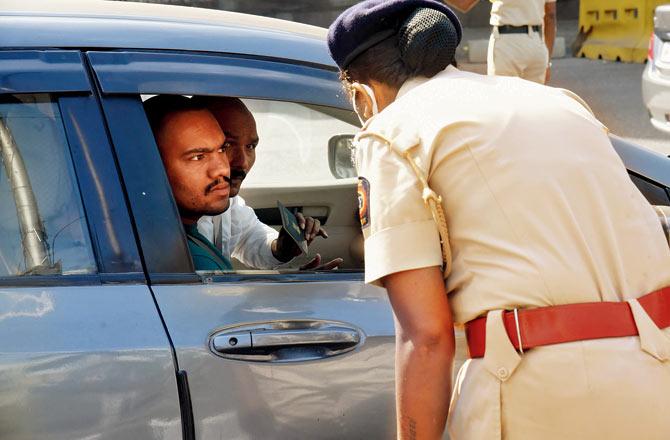 A police officer asks a driver his purpose for travelling near Mulund Toll plaza on Monday. Pic/Sameer Markande