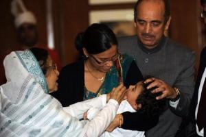 Former President Pratibha Patil (left) holds a child as former Health Minister Ghulam Nabi Azad (right) administers polio drops to a child during a Polio Free India campaign. (Photo: AFP)