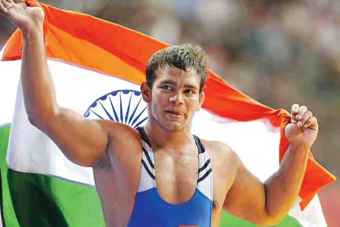 India wrestler Narsingh Yadav holds the national flag after winning the 74kg men’s freestyle match at the Commonwealth Games at New Delhi in 2010. pic/AFP