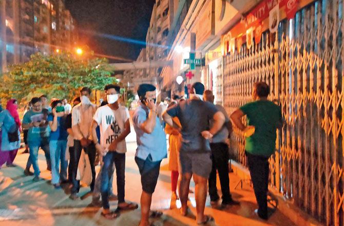 Panic buyers queue outside half-opened grocery shops at 9 pm in Virar