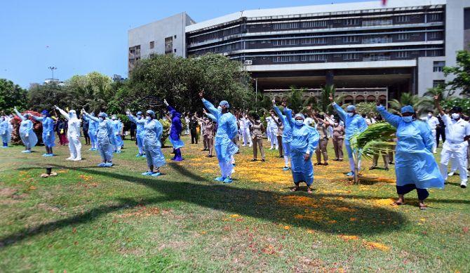 Masked health workers greet and wave at helicopters that showered flower petals on them. The Armed forces thanked the health workers for relentlessly carrying out their fight against COVID-19