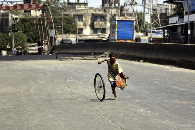 In photo: A kid enjoys a game with a bicycle tyre on an empty road in the streets of Dharavi amid lockdown in the city.