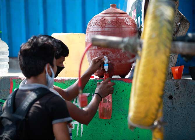 Migrant workers fill water from earthen water dispensers that have been installed in some parts of Mumbai.