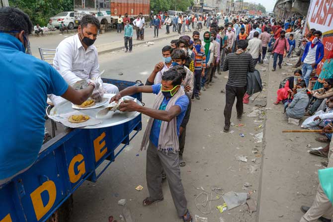 In picture: In Jalandhar, volunteers distribute food to migrant workers waiting to board special buses to go to their native places in Uttar Pradesh and Bihar.