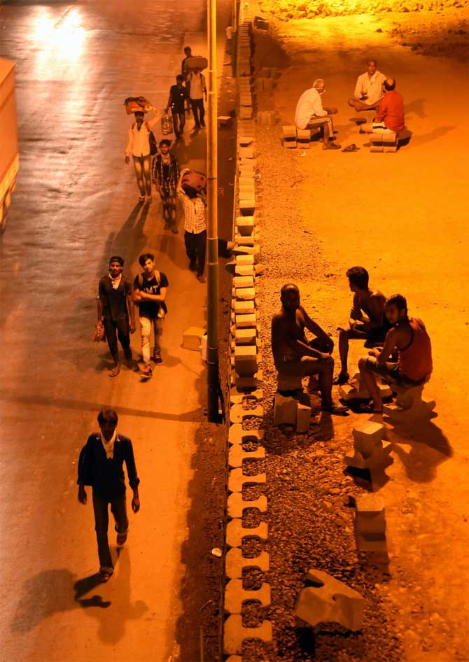As many as 334 COVID-19 patients were discharged from hospitals in Mumbai during the day, taking the number of recovered patients to 4,568, the civic body said.
In picture: Migrant workers walk along the Thane-Nashik Express Highway as locals look on.