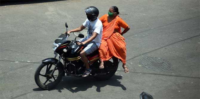 Earlier, the BMC acquired Worli-based National Sport Club of India's indoor stadium to set up quarantine and isolation facilities.
In picture: A biker rides on the city road with an elderly woman.