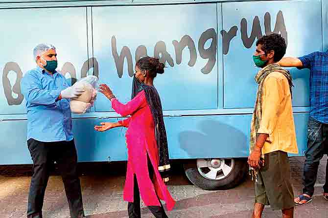 A volunteer distributes food kits to the underprivileged