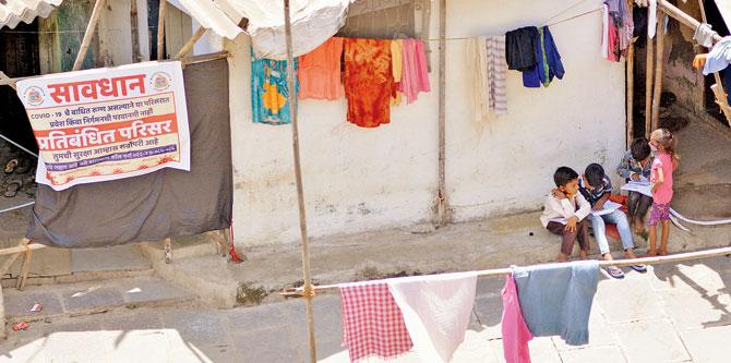Children living in a Tilaknagar slum study next to a banner declaring it a containment zone on Wednesday. Pic/Sayyed Sameer Abedi