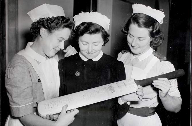 Three medical staffers inspecting the autographed bat presented by England batsman Bill Edrich to the Woolwich Memorial Hospital in order to raise funds. Pic/Getty Images