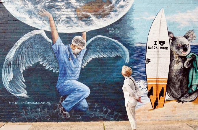 A woman looks at a mural of a health worker with wings holding a globe on International Nurses Day on Tuesday. Pics/AFP