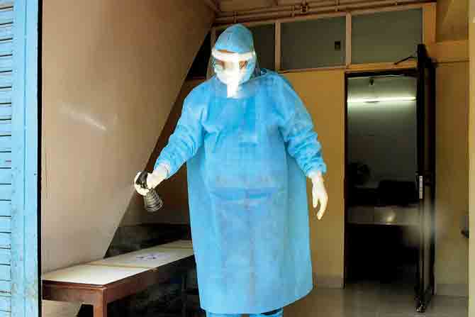 Dr Mohan Tipre, a private practitioner at Dharavi, disinfects his clinic before the arrival of patients, while wearing PPE. PIC/Suresh Karkera