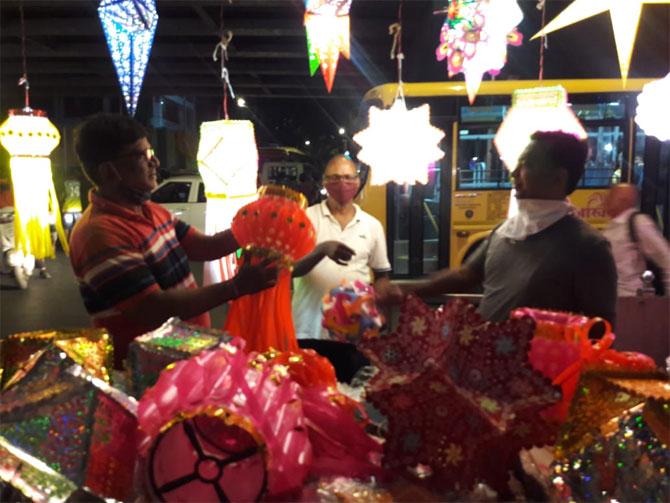 A lantern seller shows a customer the variety of lanterns on sale for Diwali at Mahim's Kandil Galli.