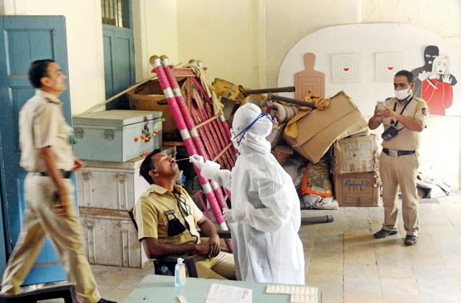 Health workers at a COVID-19 screening and swab testing facility for city cops at Aarey police station, Goregaon. File pic