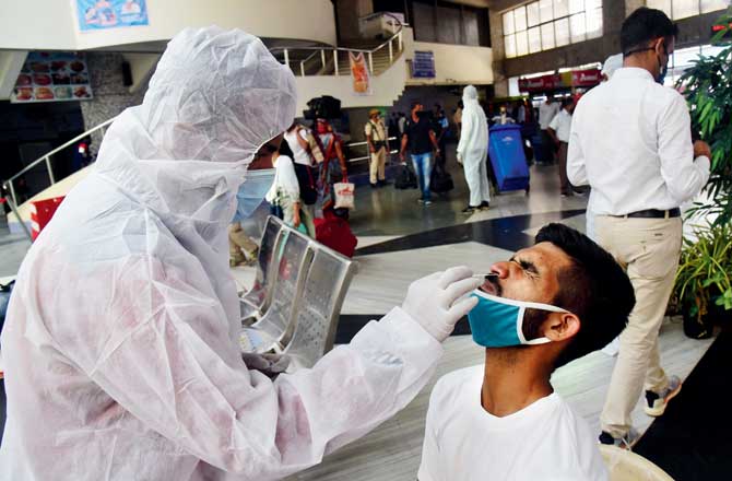 Medical personnel collect swab samples for a COVID-19 test from arriving passengers at Bandra Terminus on Sunday. Pic/Shadab Khan;