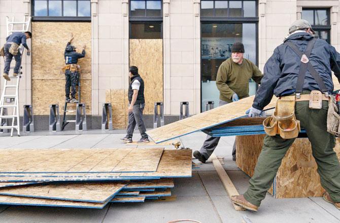 Workers with Baguer Construction LLC board up a Walgreens on U Street NW. File pic/AP