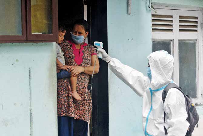 a health worker scans the temperature of a resident of Nutan Ayojan Nagar in Malad