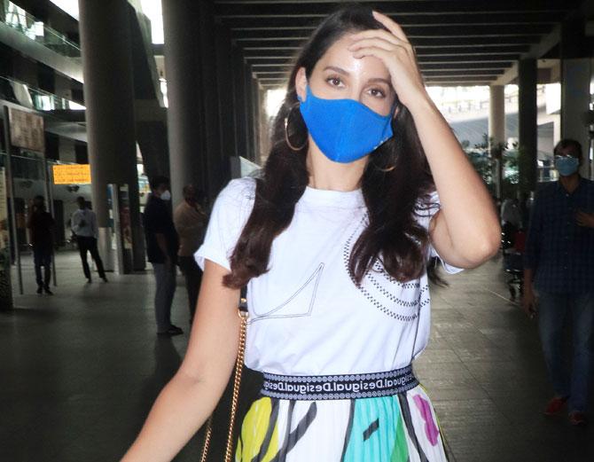 The Street Dancer actress Nora Fatehi was clicked at the Mumbai airport. Nora looked pretty in her white top, a pleated skirt with abstract print and a blue protective face mask. Fatehi returned from Goa, where she had taken a short break after her stint on India's Best Dancer. All pictures/Yogen Shah