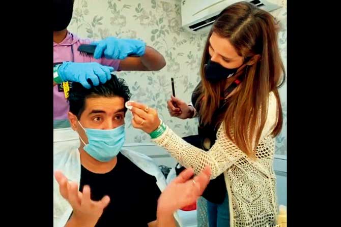 A masked Manish Malhotra is attended to by his team on the set