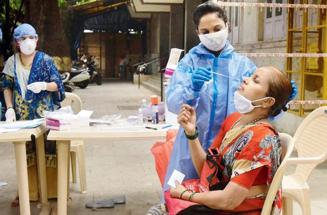 A health worker collects a swab sample at a Health Care Centre in Dadar. File pic