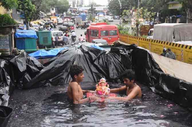 Various wings of the police department were manning the streets and the security personnel were also keeping a close watch on the immersion with the help of about 5,000 CCTVs, the official said.
In picture: Two boys immerse a Ganesha idol in a makeshift pond in Santacruz.