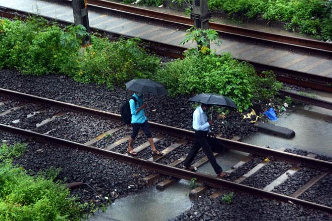 In picture: Commuters walk on railway tracks as heavy rain caused flooding.