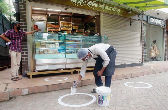 A shopkeeper draws circles outside his shop in Dadar to facilitate social distancing. Pic/Ashish Raje