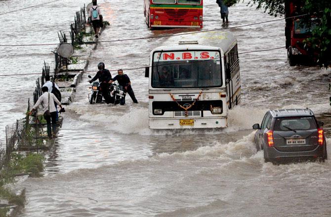 People and vehicles try to navigate a small lake formed on LBS Road between Kurla and Ghatkopar. Pic/Sayyed Sameer Abedi