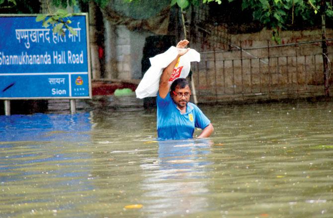 A man tries to wade through almost chest-deep water near Shanmukhananda Hall in King