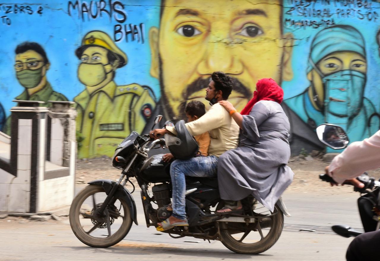 On April 22, the Western and Central Railway also issued circulars stating that only essential workers will be allowed to use the Mumbai local trains. The restrictions, which came into effect from 8 pm on April 22 will be in place till 7 am on May 1.
In photo: A biker without a mask and helmet as he rides past a wall mural on COVID-19 awareness at Andheri. Photo: Shadab Khan