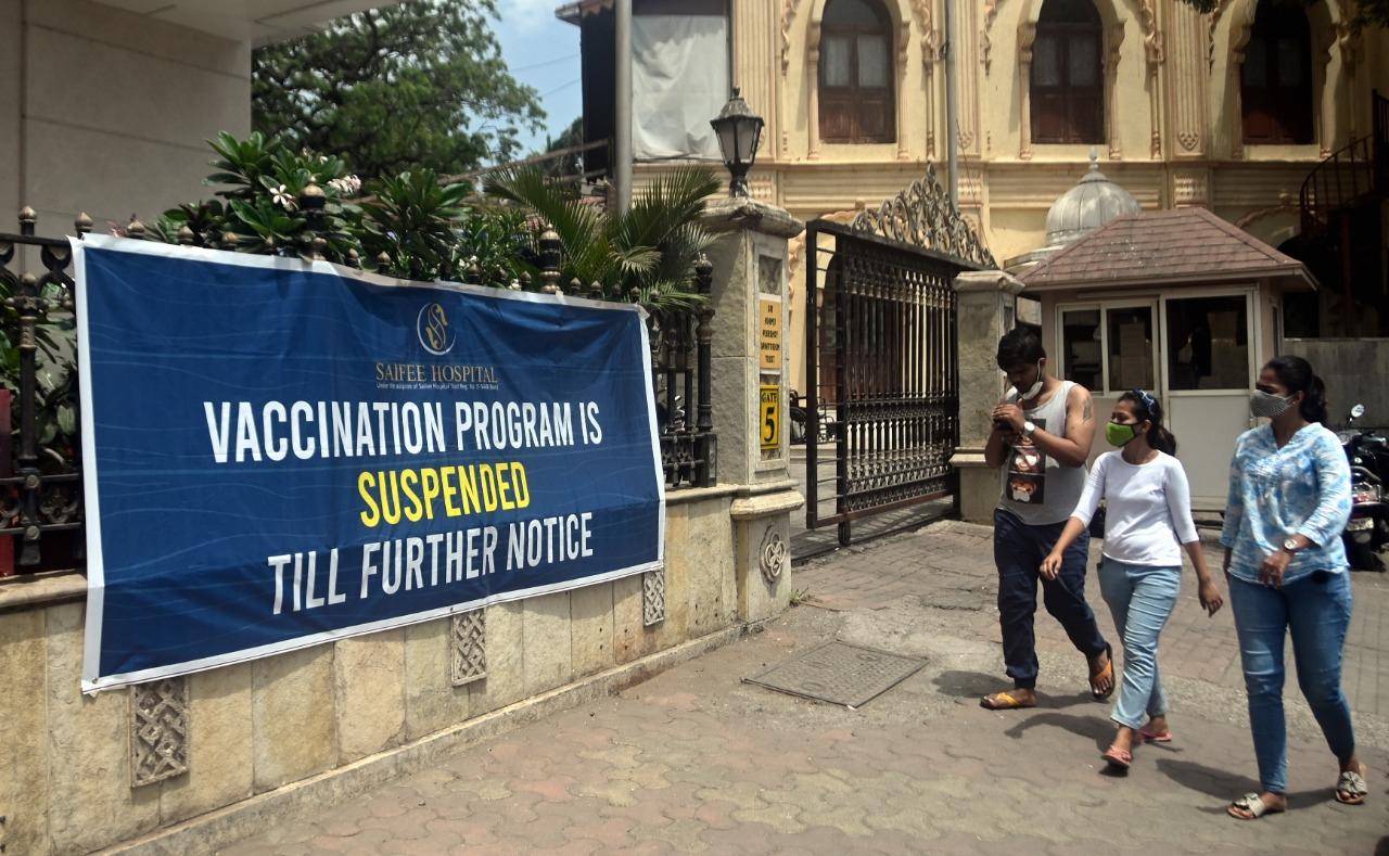 In photo: A group of youngsters walk past a banner that read 'Vaccination program is suspended till further notice' outside Saifee hospital in South Mumbai. Photo: Bipin Kokate