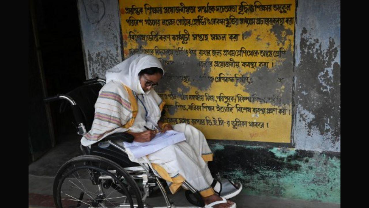 West Bengal`s Chief Minister Mamata Banerjee takes notes while sitting in a wheelchair at a polling station during Phase 2 of West Bengal`s legislative election in Nandigram on Thursday. Pic/AFP