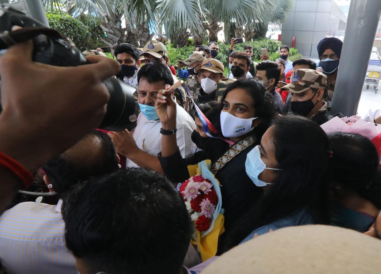 Reigning world champion Sindhu, who had won a silver at the Rio Games five years ago, walked out of the Indira Gandhi International Terminal amid a round of applause from the airport staff. She was flanked by security officers and wearing a face mask