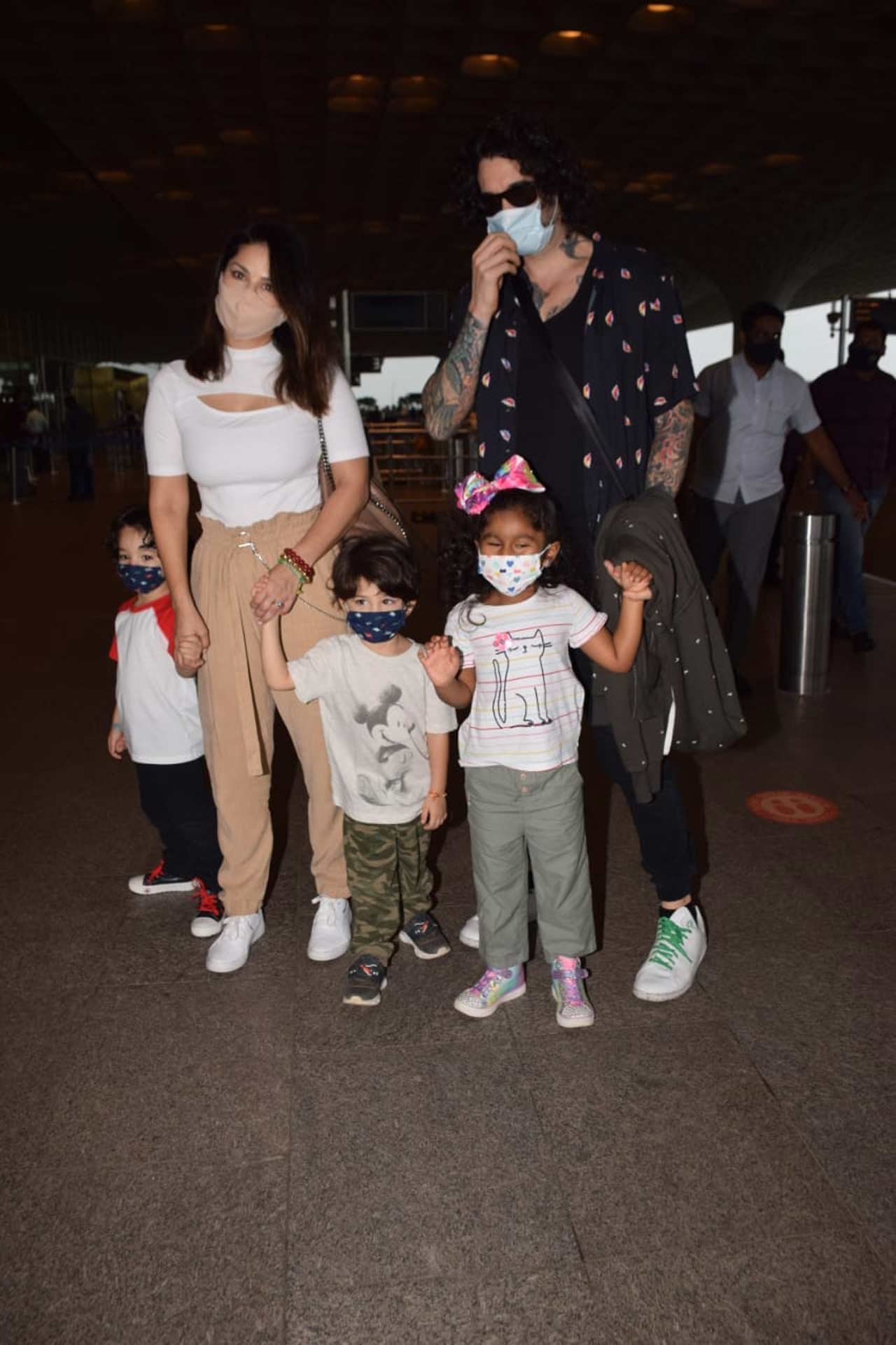 Sunny Leone, Daniel Weber, Nisha Kaur Weber, Asher and Noah Singh Weber were clicked together at the Mumbai airport. The actress was seen wearing a white crop top, which she paired with beige coloured pants.