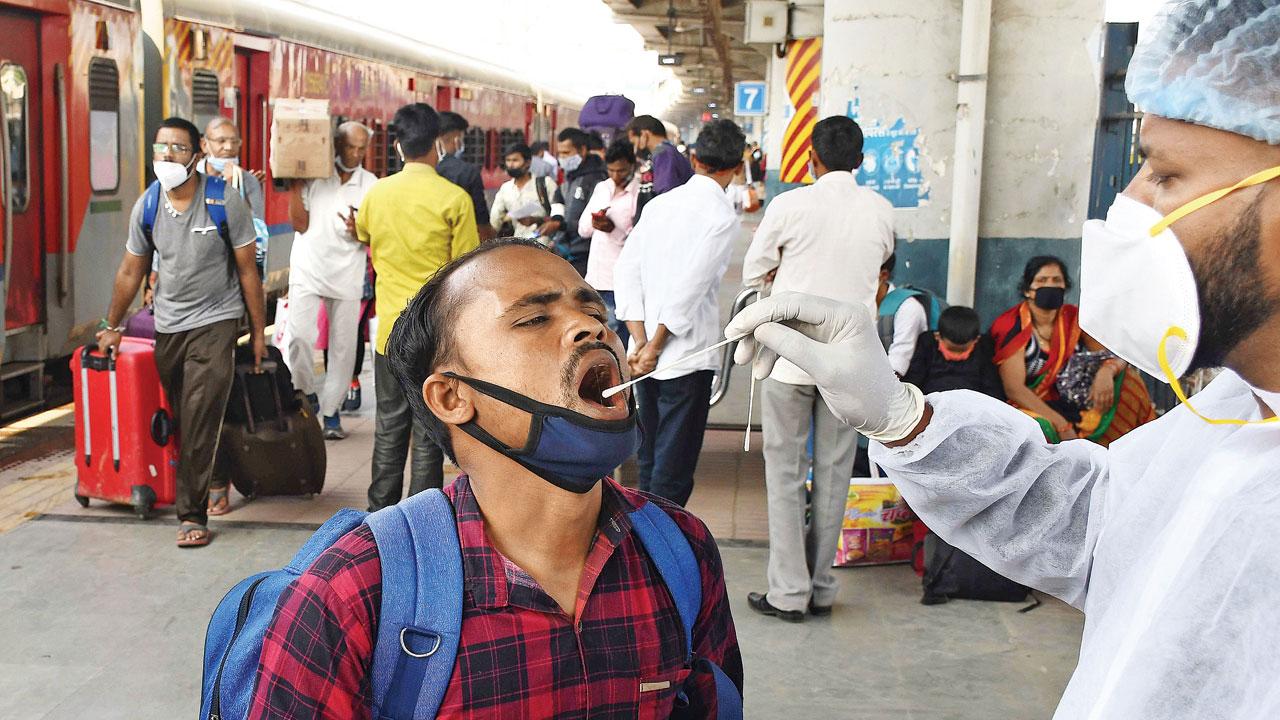A BMC health worker collects the swab sample of passenger for Covid-19 test after he arrived at Dadar station aboard a Bhuj train, on Friday. Pic/Ashish Raje