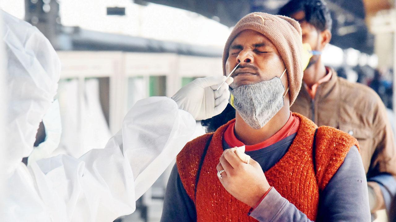 A civic health worker collects a swab sample of a passenger for Covid-19 test, at Lokmanya Tilak Terminus, Kurla, on Sunday. Pic/Sameer Markande