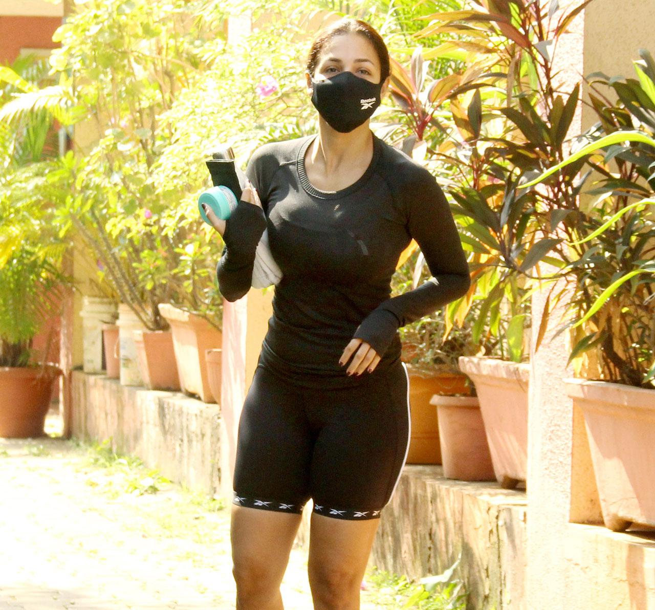Malaika Arora dressed in all black athleisure attire of tee and gym shorts as she was clicked arriving at her Yoga Studio in Bandra. Abiding by COVID-19 restrictions, the fitness diva wore a matching face mask.