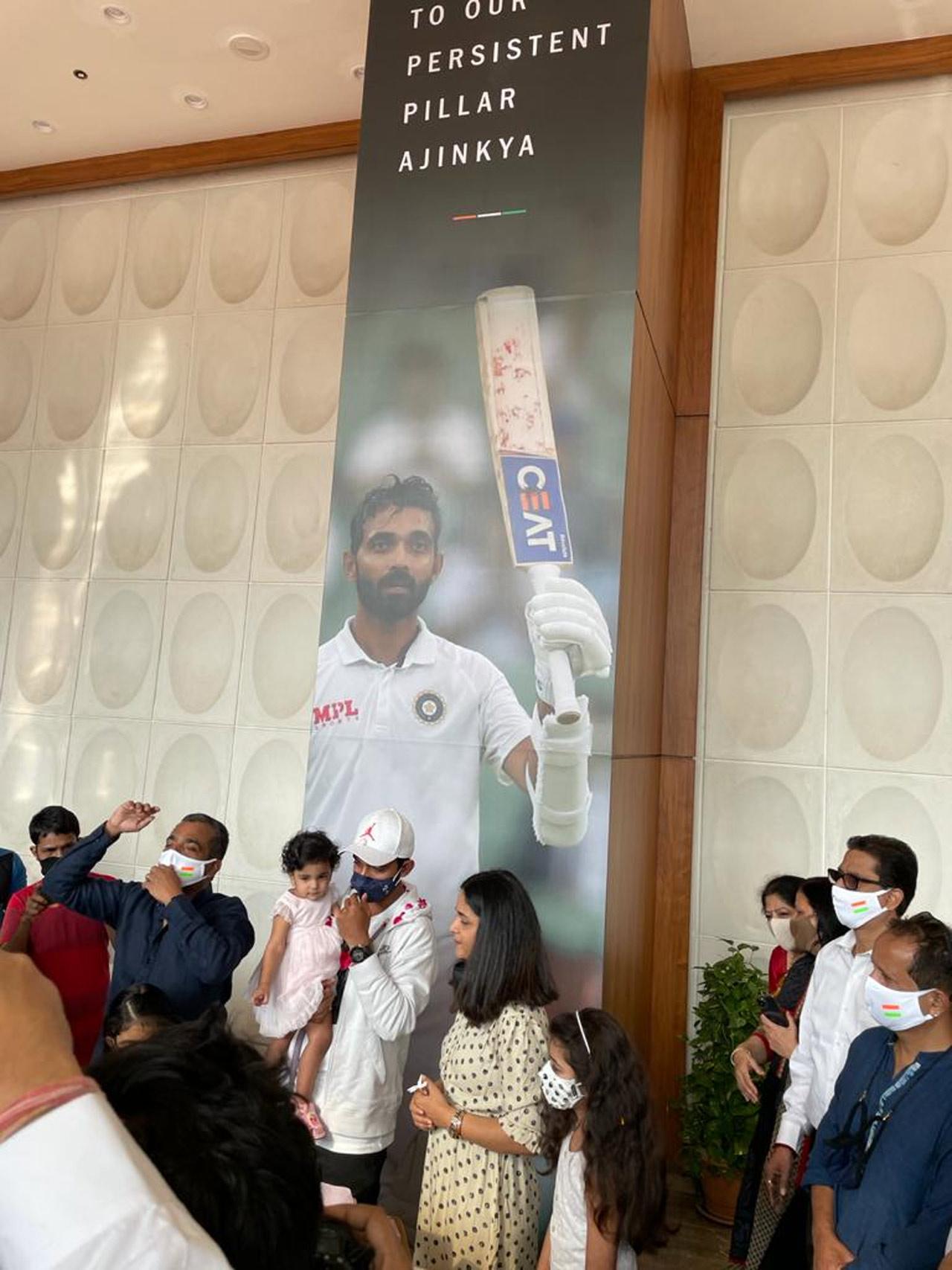 Team India won the fourth and final Test at The Gabba in historic fashion by 3 wickets after they lost the first Test, won the second Test and drew the third. In pic: Rahane with wife Radhika and daughter Aarya next to a portrait honouring him at his residence in Matunga. Picture/ mid-day reader Shripal Sangvi