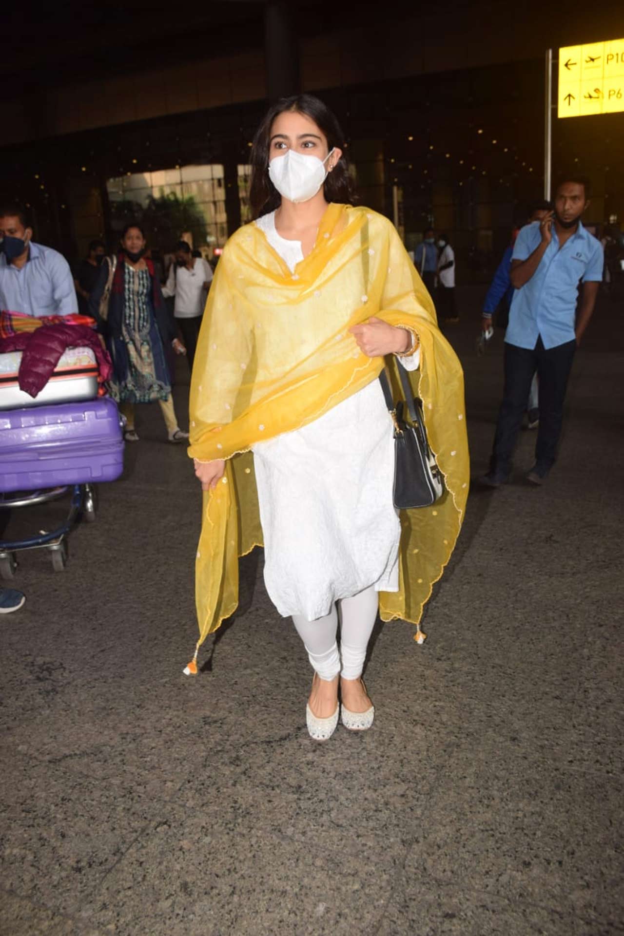 Sara Ali Khan was snapped wearing an ethnic dress at the Mumbai airport. She was seen wearing a white dress, paired with a pretty yellow organza dupatta during her outing. All pictures/Yogen Shah