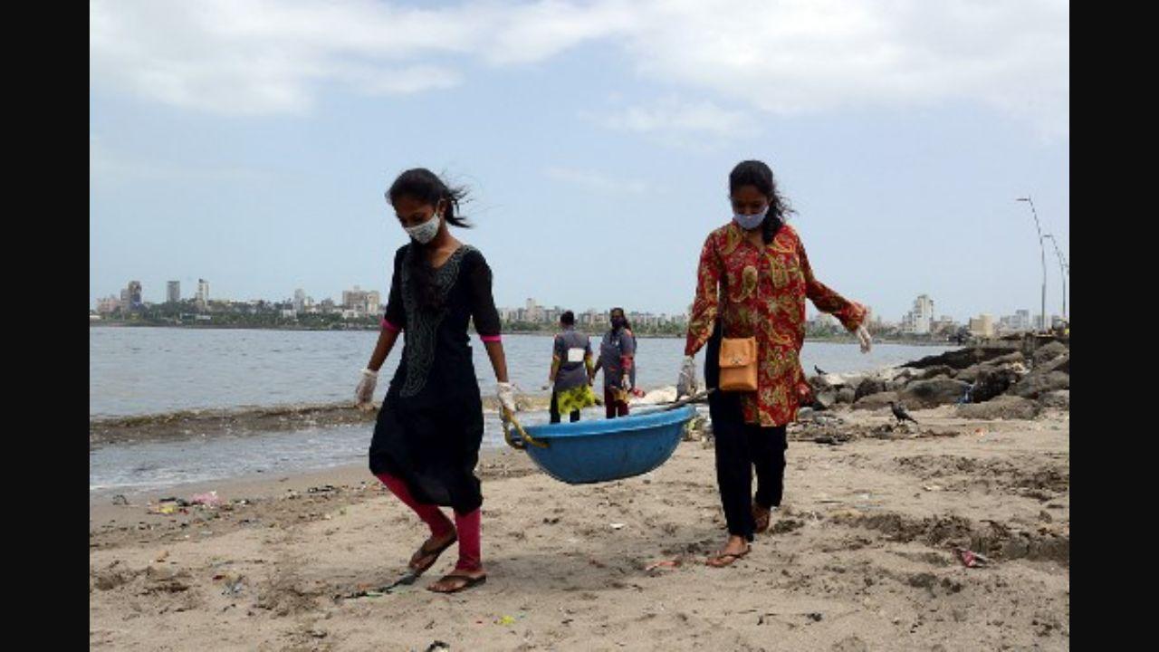 Local residents take part in a beach clean-up effort to remove waste and garbage at Mahim beach in Mumbai on June 26, 2021. This is one of the many beach cleanups conducted in the city over the years. Most notably, Afroz Shah, a city-based lawyer and UN's 2016 Champion of Earth has been actively involved in beach cleanups since 2015 when he started the biggest one at Versova beach.  Photo: AFP