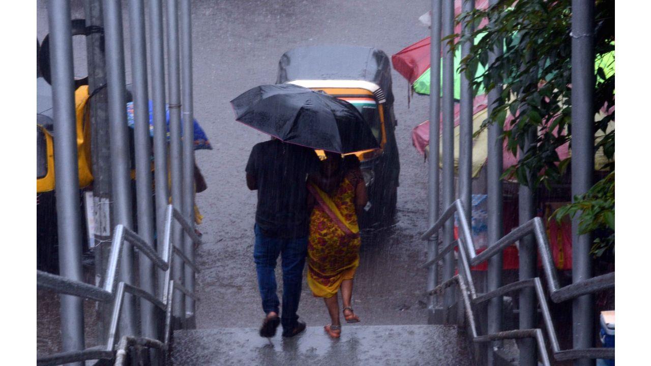 Two people share an umbrella as rains lash Bandongri area in Kandivli on Monday. Pic/ Satej Shinde