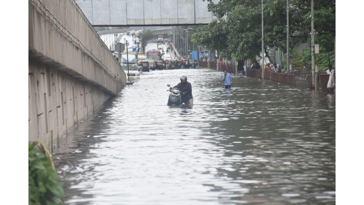 A rider walks with his two-wheeler on a water-logged road near Lokmanya Tilak Terminus in Kurla. Pic/ Sameer Markhende