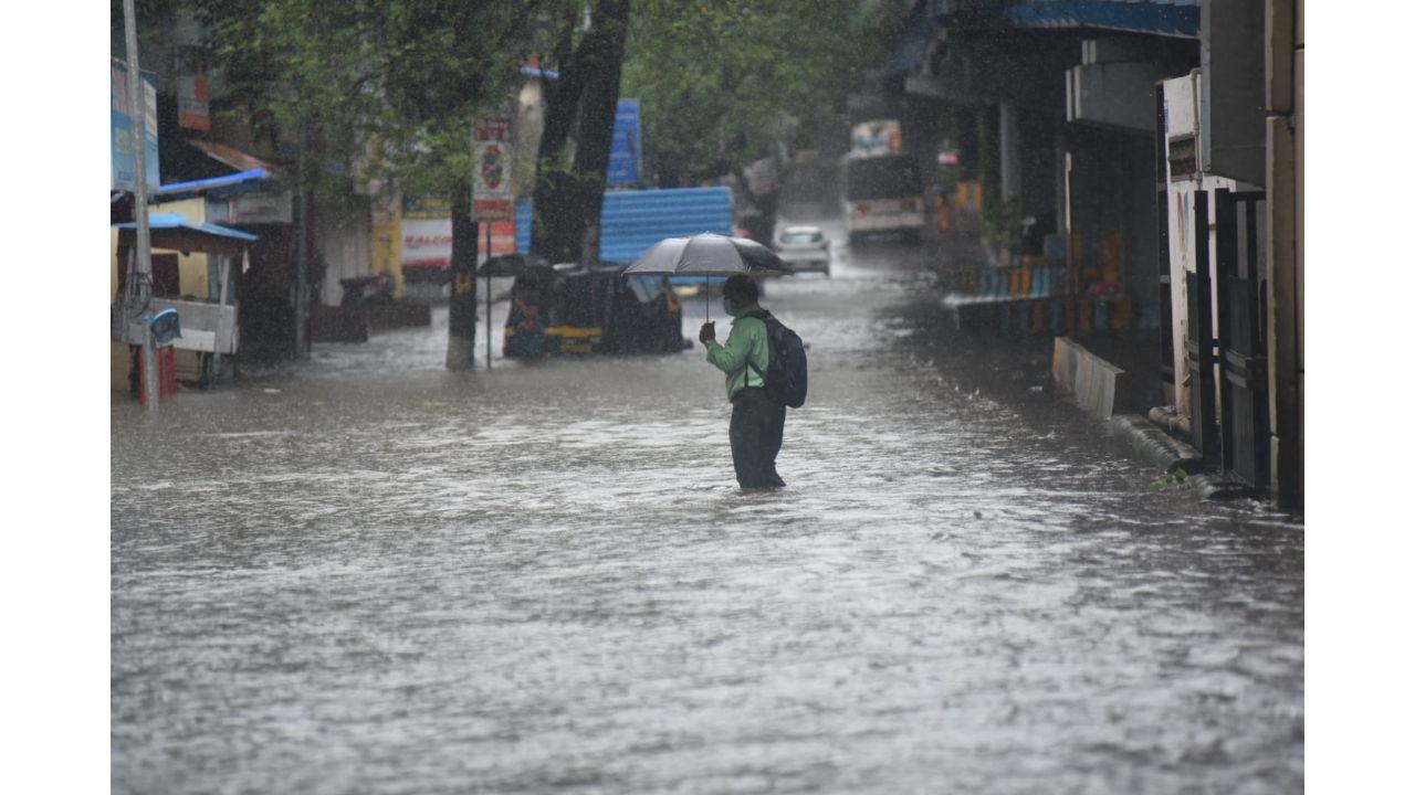 A commuter waits amid the downpour at Malhar Cinema road in Thane (West). Pic/ Sameer Markhende