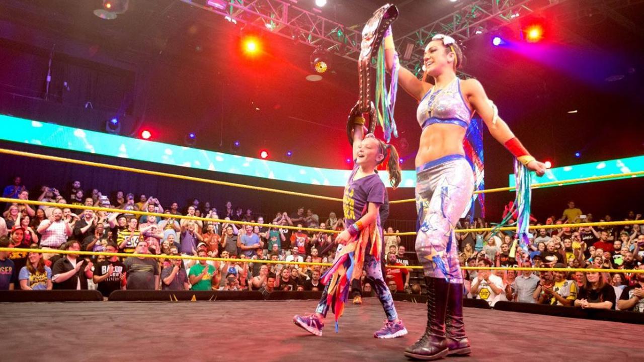 WWE former SmackDown women's champion Bayley accompanies a WWE fan in the ring.